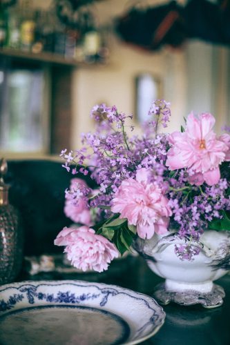 bright pink peonies in vase near ornamental plate on table