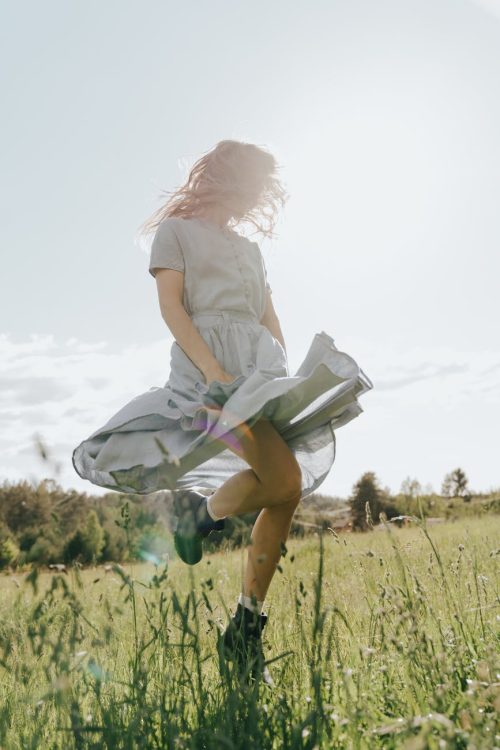 girl in white t shirt and blue shorts running on green grass field